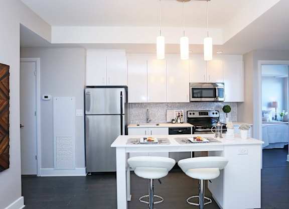 a kitchen with white cabinets and a white island with white chairs