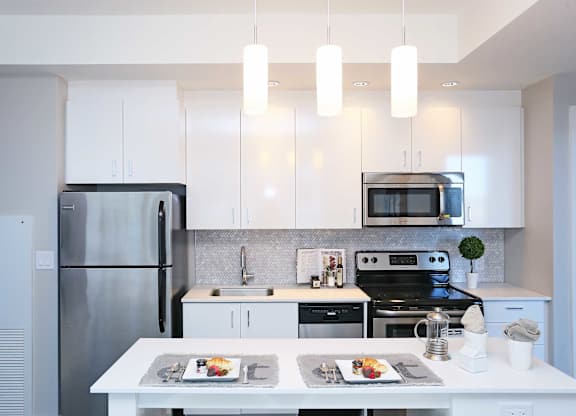 a white kitchen with stainless steel appliances and white cabinets