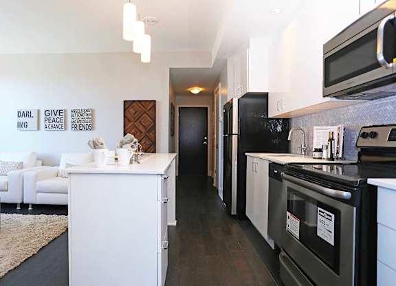 a kitchen and living room with black appliances and white cabinets