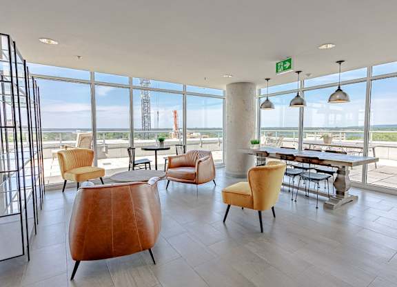 a lobby with chairs and tables and a view of a refinery