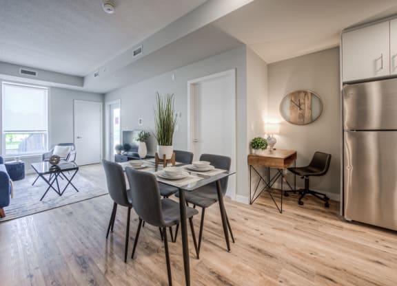 a dining area with a table and chairs and a stainless steel refrigerator
