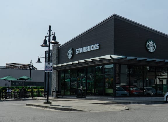 A Starbucks storefront with a car parked in front.