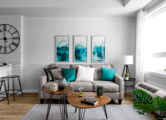 a living room with a gray couch and turquoise pillows