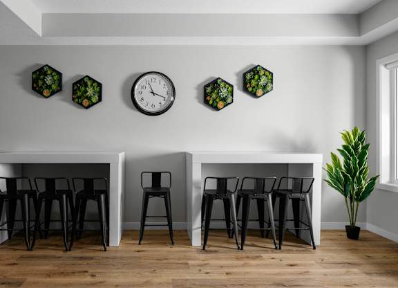 A white table with black chairs and a clock on the wall.