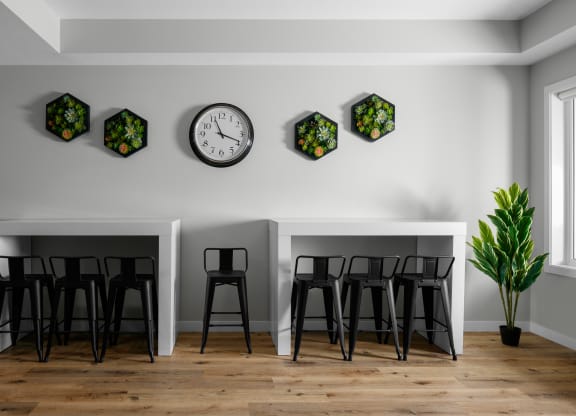 two tables and three stools in a room with a clock on the wall