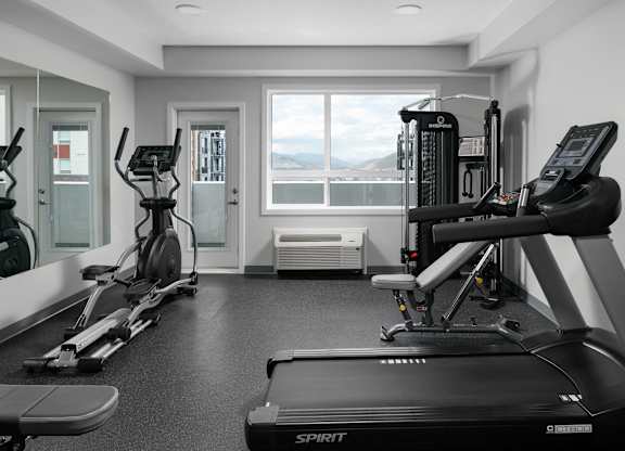 A black and white photo of a gym with a treadmill in the foreground.