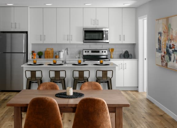 a kitchen with white cabinets and a large island with a wooden table and chairs