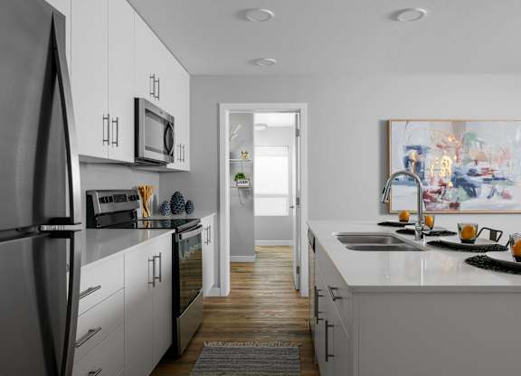 A modern kitchen with white cabinets and a refrigerator.