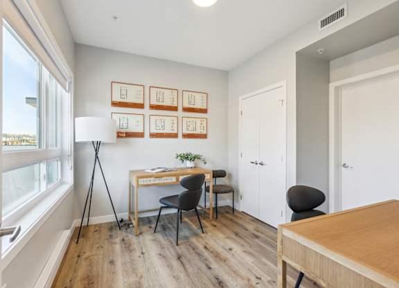 A room with a desk, chairs, and pictures on the wall.