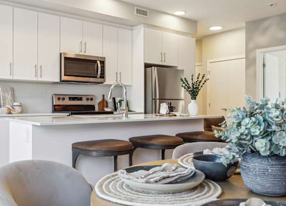 A modern kitchen with white cabinets and a breakfast table set.