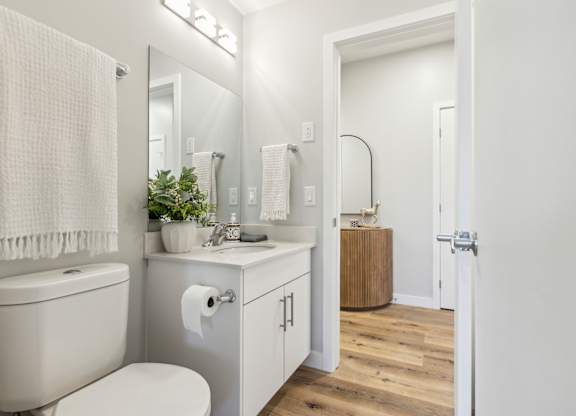 A white bathroom with a toilet, sink, and mirror.