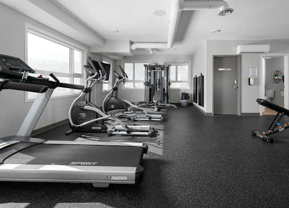 A gym with treadmills, elliptical machines, and other exercise equipment.