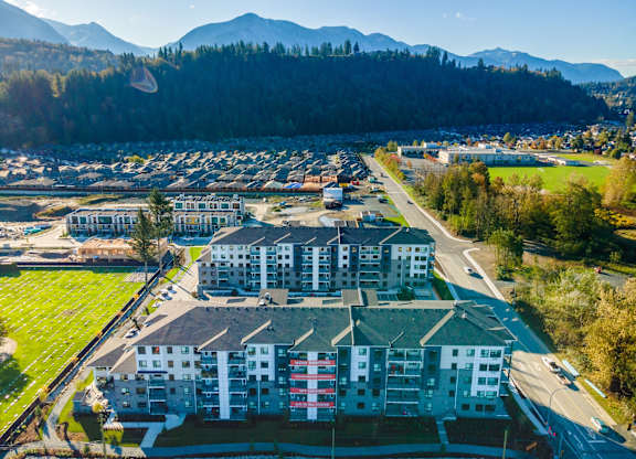 A large apartment complex with a parking lot in front and mountains in the background.