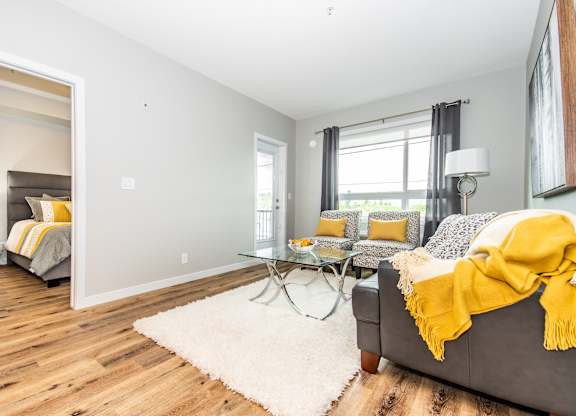 A bedroom with a grey couch and a yellow blanket.