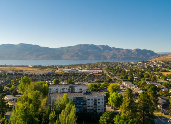 a cityscape with a lake and mountains in the background