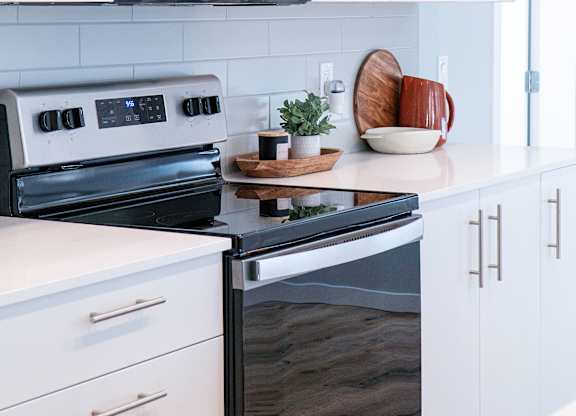 A modern kitchen with a black oven and white cabinets.