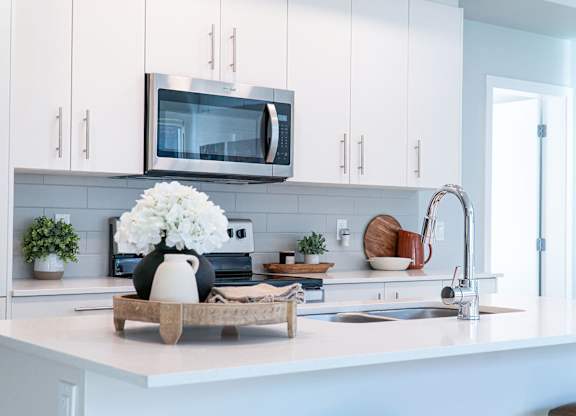 A kitchen with white cabinets and a microwave above the counter.