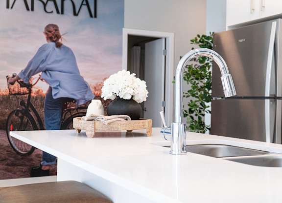 A modern kitchen with a white countertop and a stainless steel refrigerator.