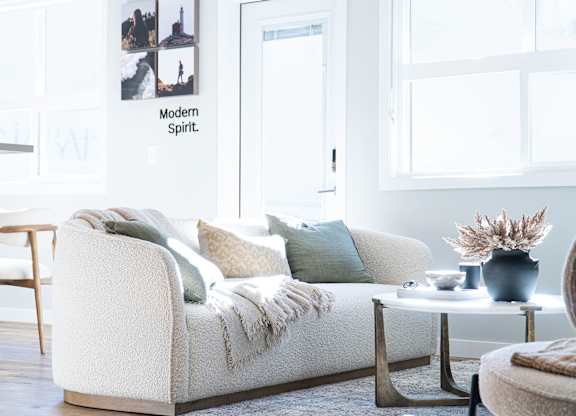 A white couch with pillows and a blanket on it.