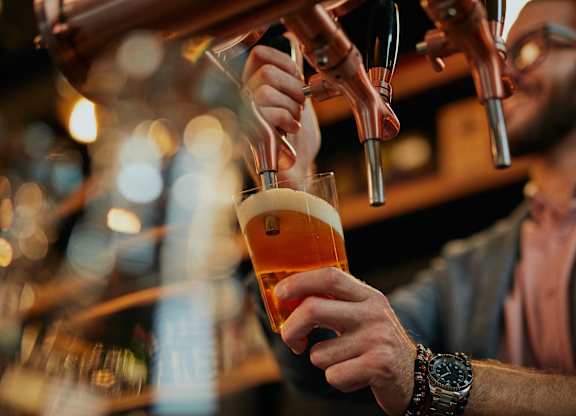 A man is pouring a beer from a tap into a glass.