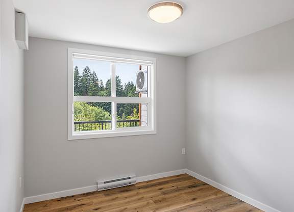 A room with a window overlooking a forest.