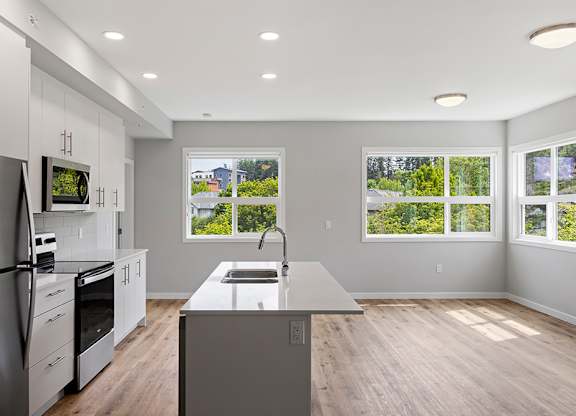 A modern kitchen with a refrigerator, oven, and sink.
