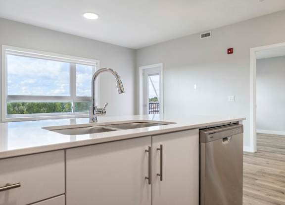 A kitchen with a stainless steel sink and white cabinets.