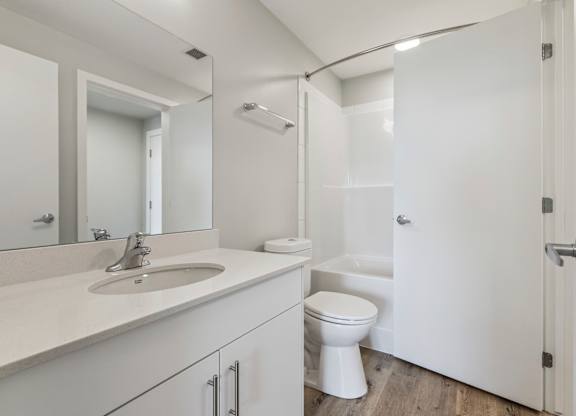 A white bathroom with a sink, toilet, and shower.