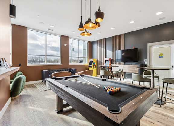 A pool table in a room with a television and chairs.