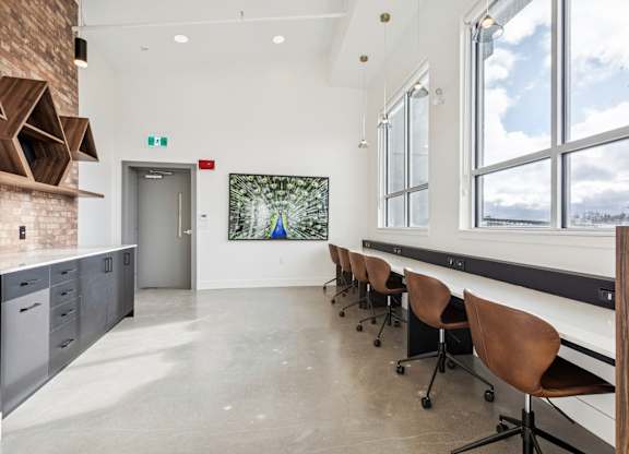 A room with a long table and chairs with a view of the outside.