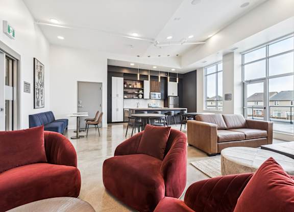 A living room with red chairs and a kitchen in the background.