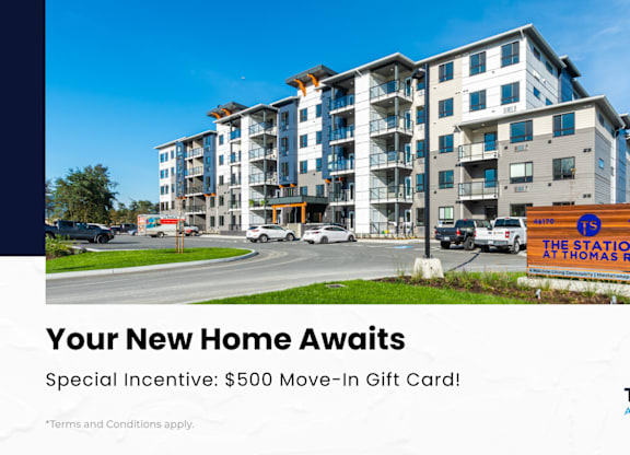 A modern apartment complex with a sign offering a $500 move-in gift card.