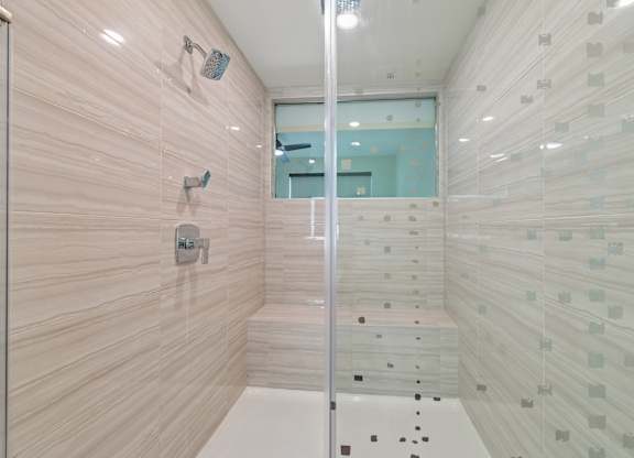 A bathroom with a glass shower stall and a glass door.