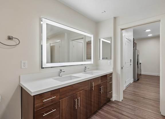 A bathroom with a white counter top and brown drawers.