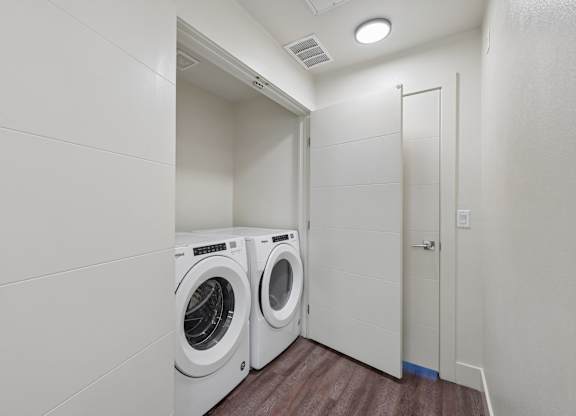 A laundry room with two washing machines and a door.
