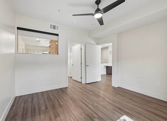 A room with a ceiling fan and wooden flooring.