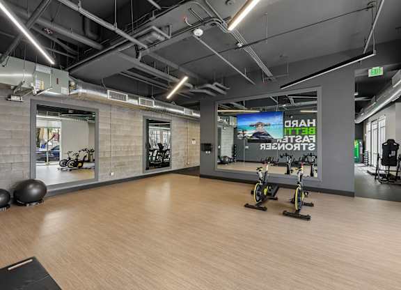A gym with a wooden floor and exercise equipment.
