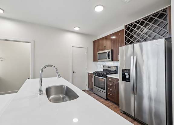 A modern kitchen with a white countertop and stainless steel appliances.
