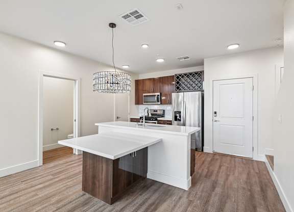 A modern kitchen with a white island and wooden floors.