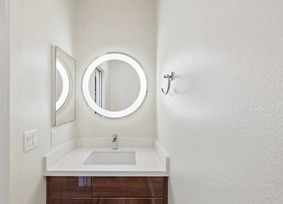 A bathroom with a round mirror and a sink.