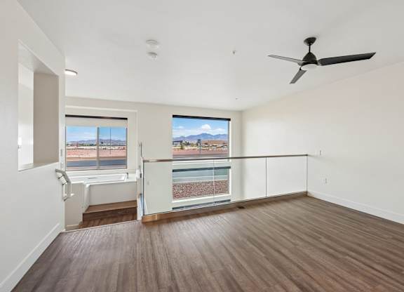 A room with a ceiling fan and a view of a pool and mountains through the window.