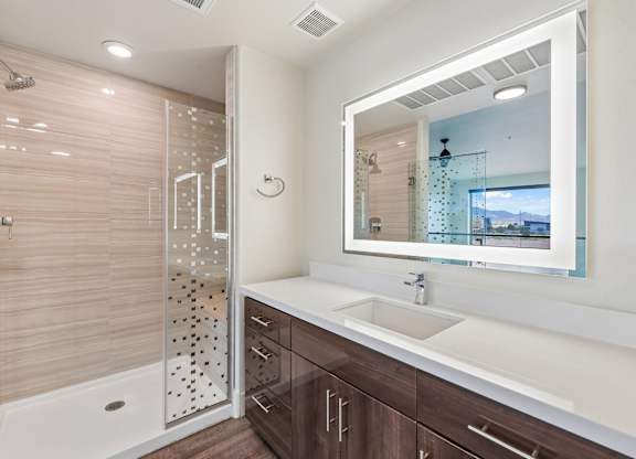 A bathroom with a walk-in shower, a sink, and a large mirror.
