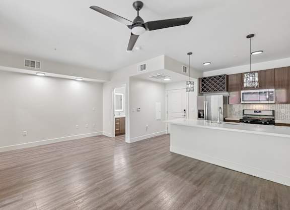 A spacious living room with a ceiling fan and hardwood flooring.