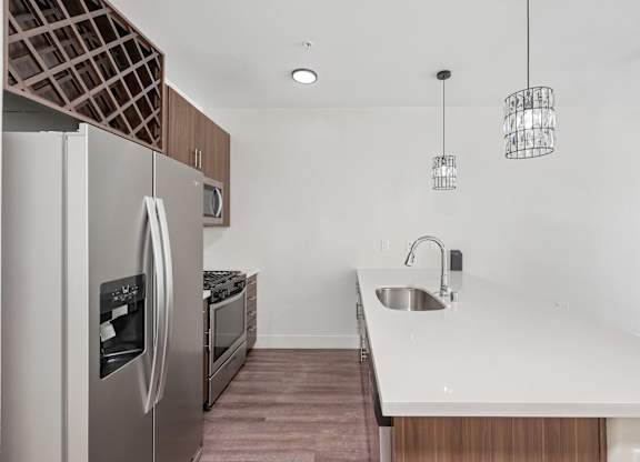 A modern kitchen with a stainless steel refrigerator and a white countertop.