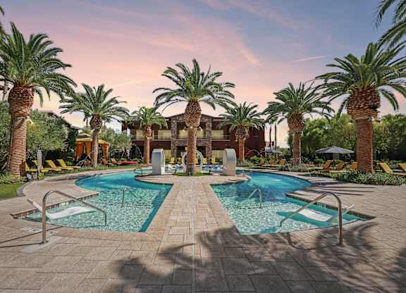 A pool surrounded by palm trees and lounge chairs.