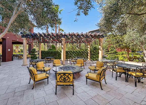 A patio with tables and chairs under a pergola.