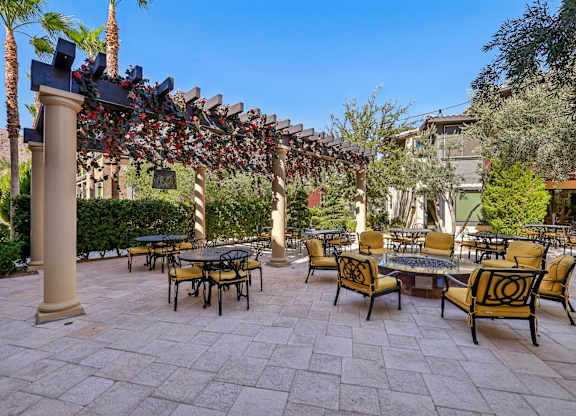 A patio with a table and chairs under a decorative arch.