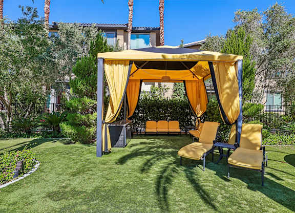 A yellow canopy is set up over a table with chairs.
