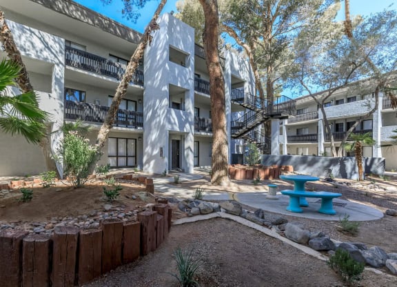a courtyard with a blue bench and a building with trees at Evoq Apartment Homes, Las Vegas Nevada  
