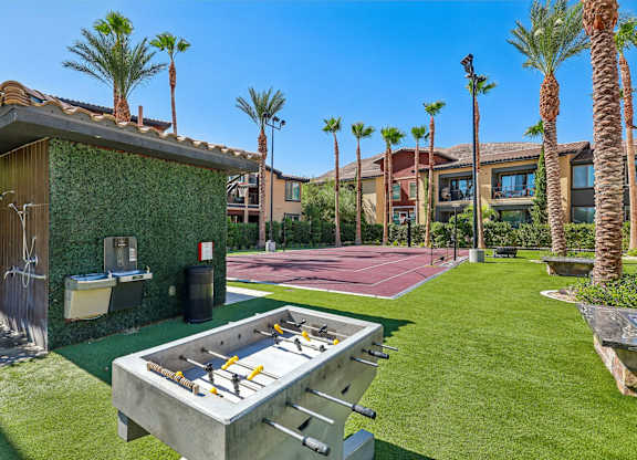 A pool table is surrounded by palm trees and a green wall.
